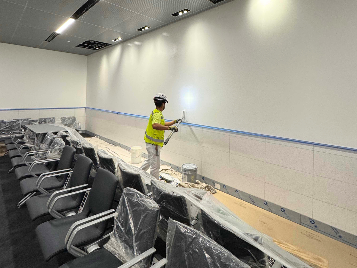 Fast-Track Projects: How We Deliver Under Tight Deadlines - Socium Coatings' painter painting with a roller the wall of an airport