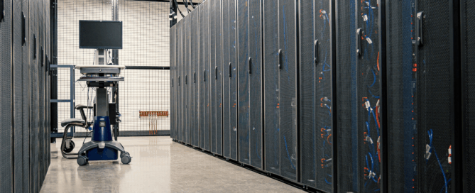 Interior of a data center room with servers, racks, organized cables, and cooling systems.