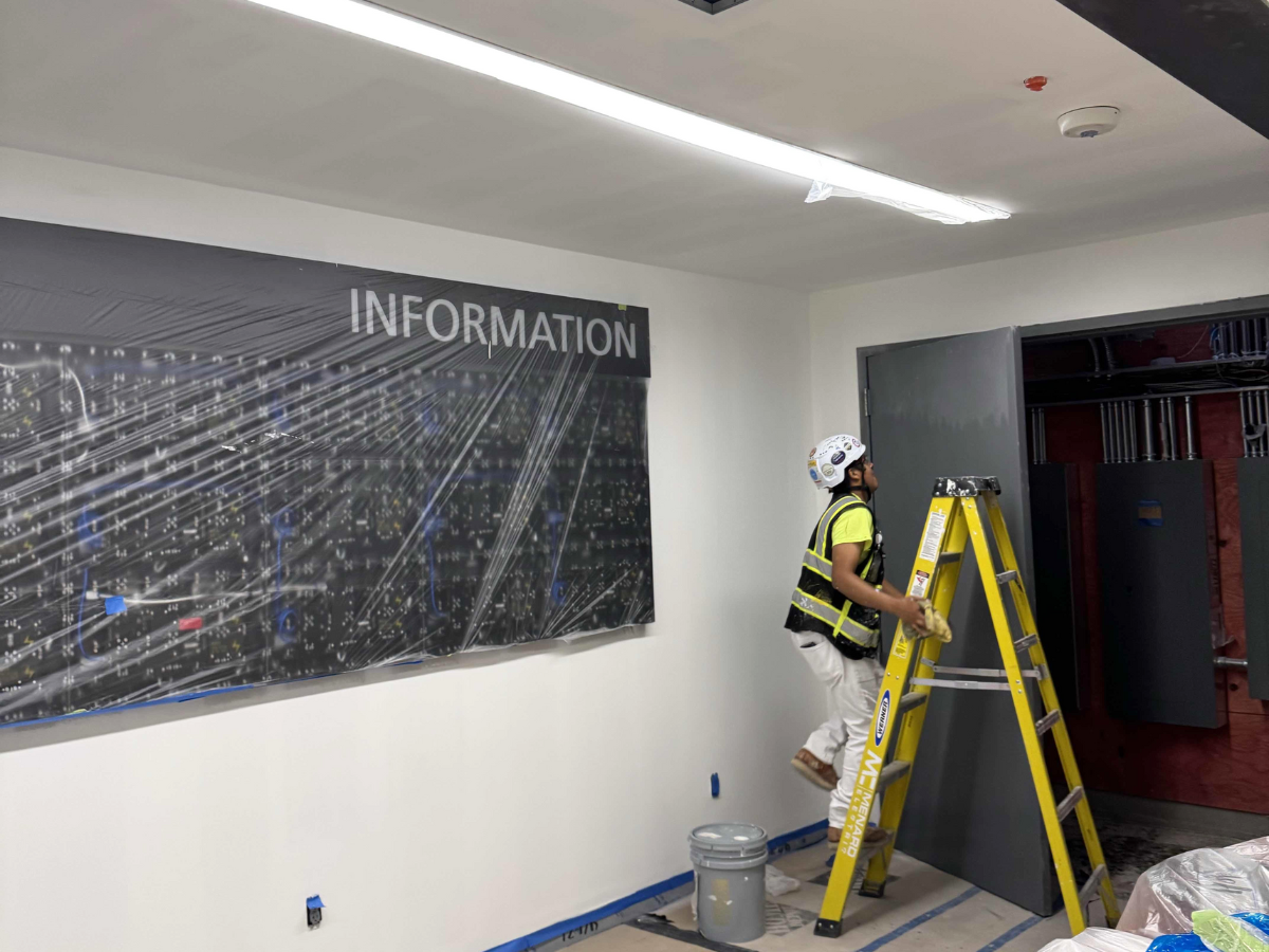 The True Cost of Cutting Corners in Coatings Projects - Painter climbing ladder in the interior of the airport