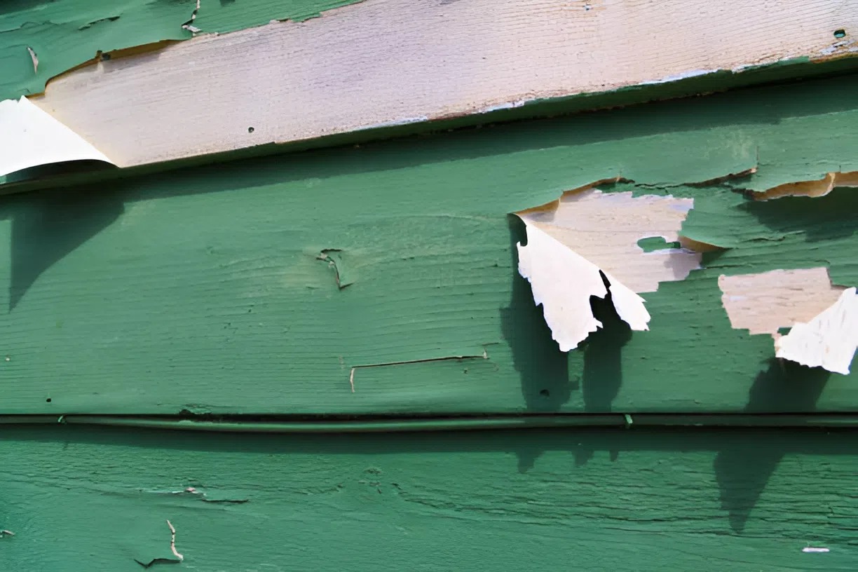 Peeling and deteriorating exterior paint on a building surface