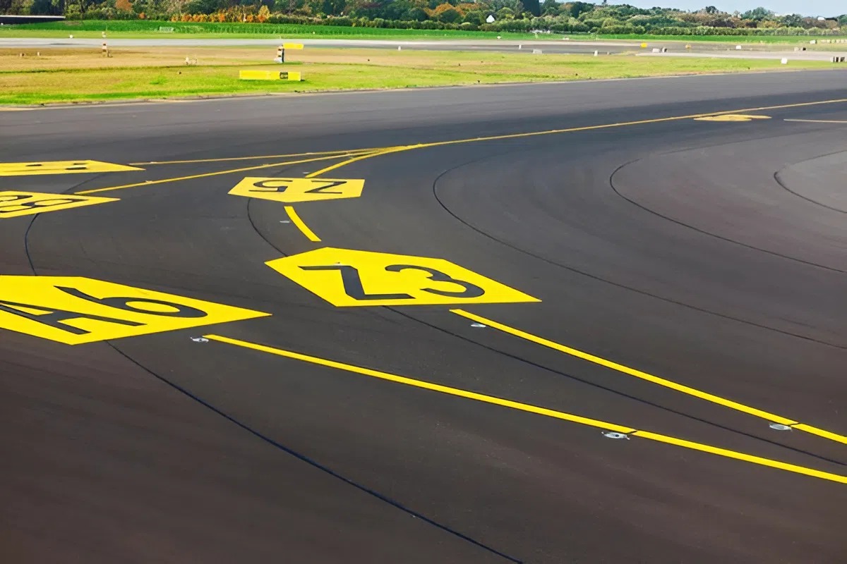 Airport runway with high-visibility yellow markings aligned with hangar interior painting safety standards