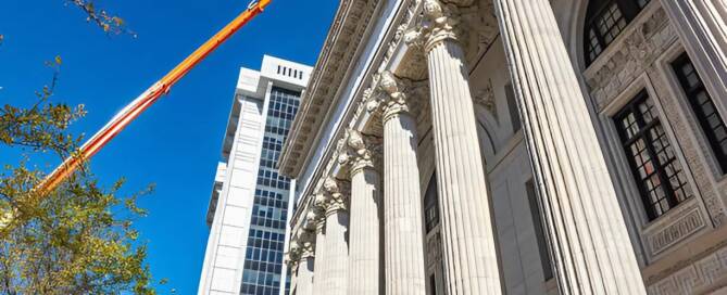 Government painting contractor in Atlanta using a boom lift to work on the exterior of a large federal building