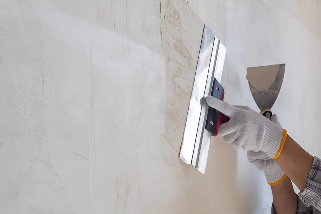 Surface preparation work by government painting contractor in Atlanta, smoothing the wall with a trowel for compliant coating application
