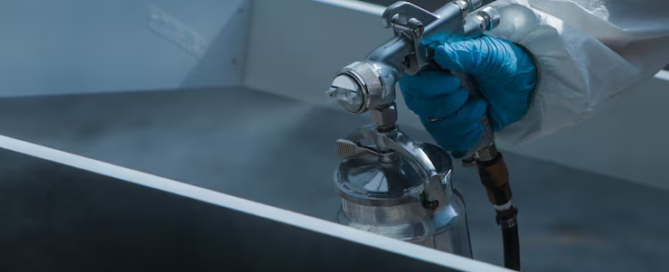 industrial protective coating applied with a spray gun to a metal surface in a manufacturing facility