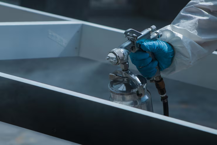 industrial protective coating applied with a spray gun to a metal surface in a manufacturing facility