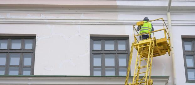 Painter applying exterior paint to a commercial building