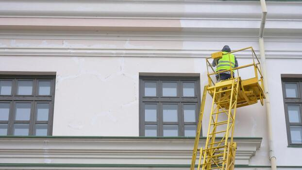 Painter applying exterior paint to a commercial building