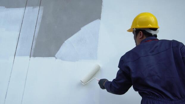 Professional painter applying paint with a roller in a commercial setting