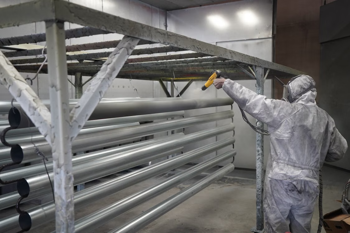 Painter applying electrostatic coatings to metal pipes