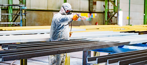 Commercial painter spraying chemical-resistant coating in an industrial facility