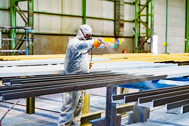 Commercial painter spraying chemical-resistant coating in an industrial facility